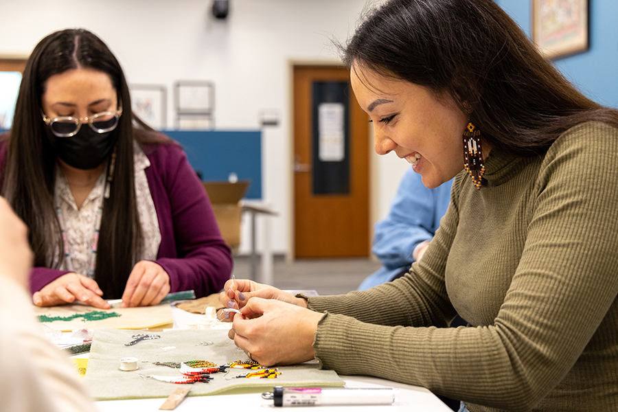 Student smiling while beading at a NACHP Crafternoon event